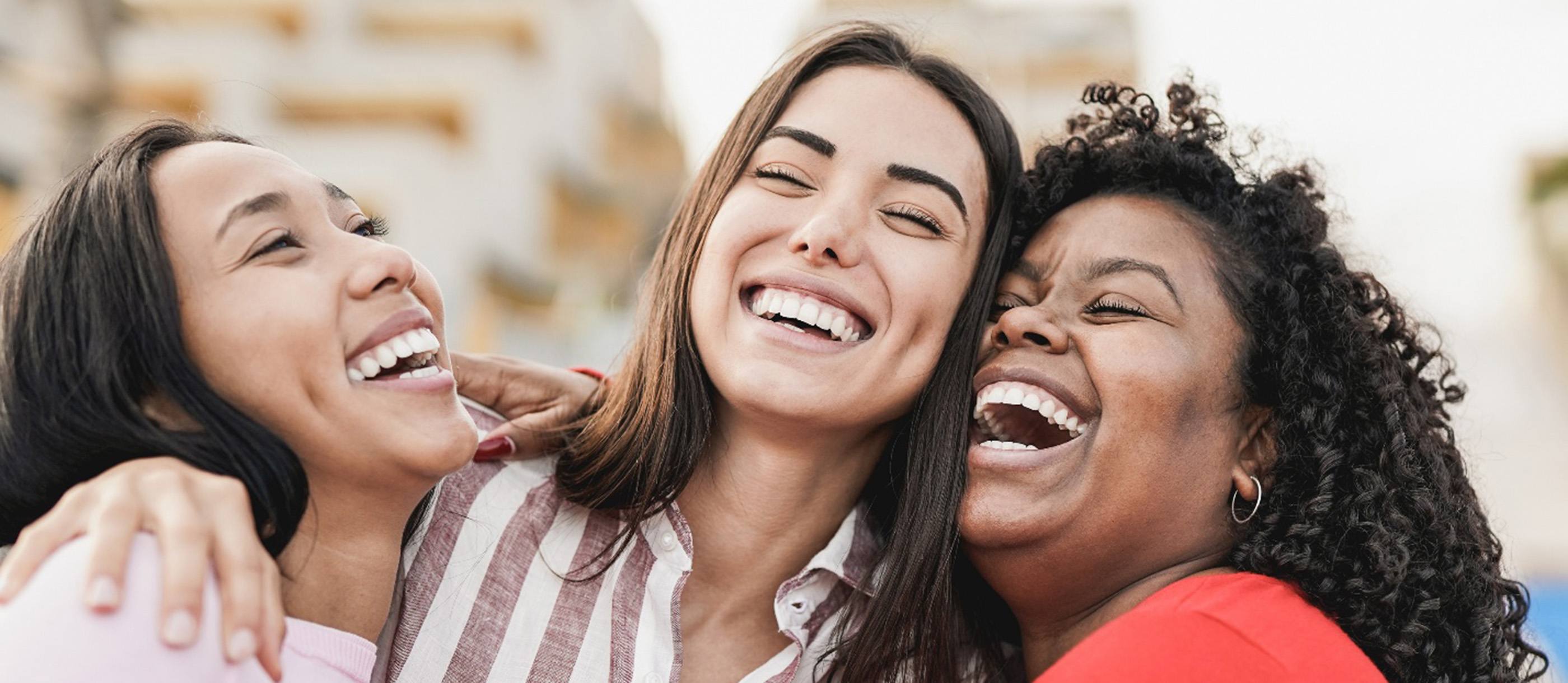 Three women laughing and smiling together after a visit with their Humana dentist in Stuart