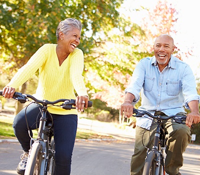 Couple smiling while riding their bike on trail